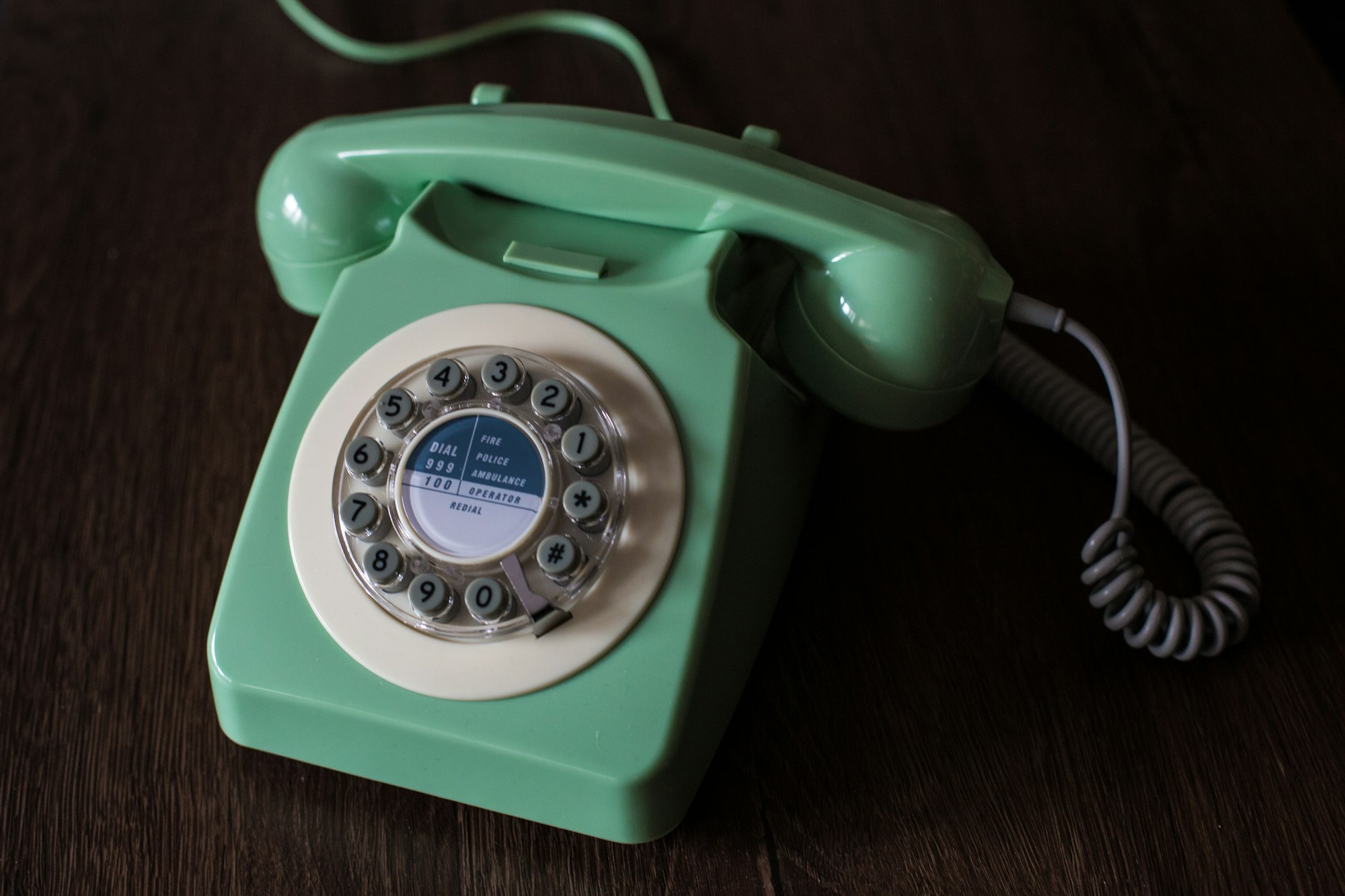 An old fashioned, vintage telephone in green with a circular dial